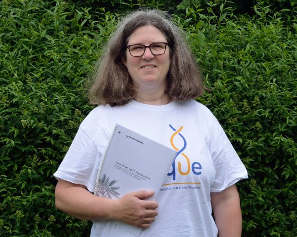 Photo shows Kristina wearing a Unique tshirt and holding her thesis